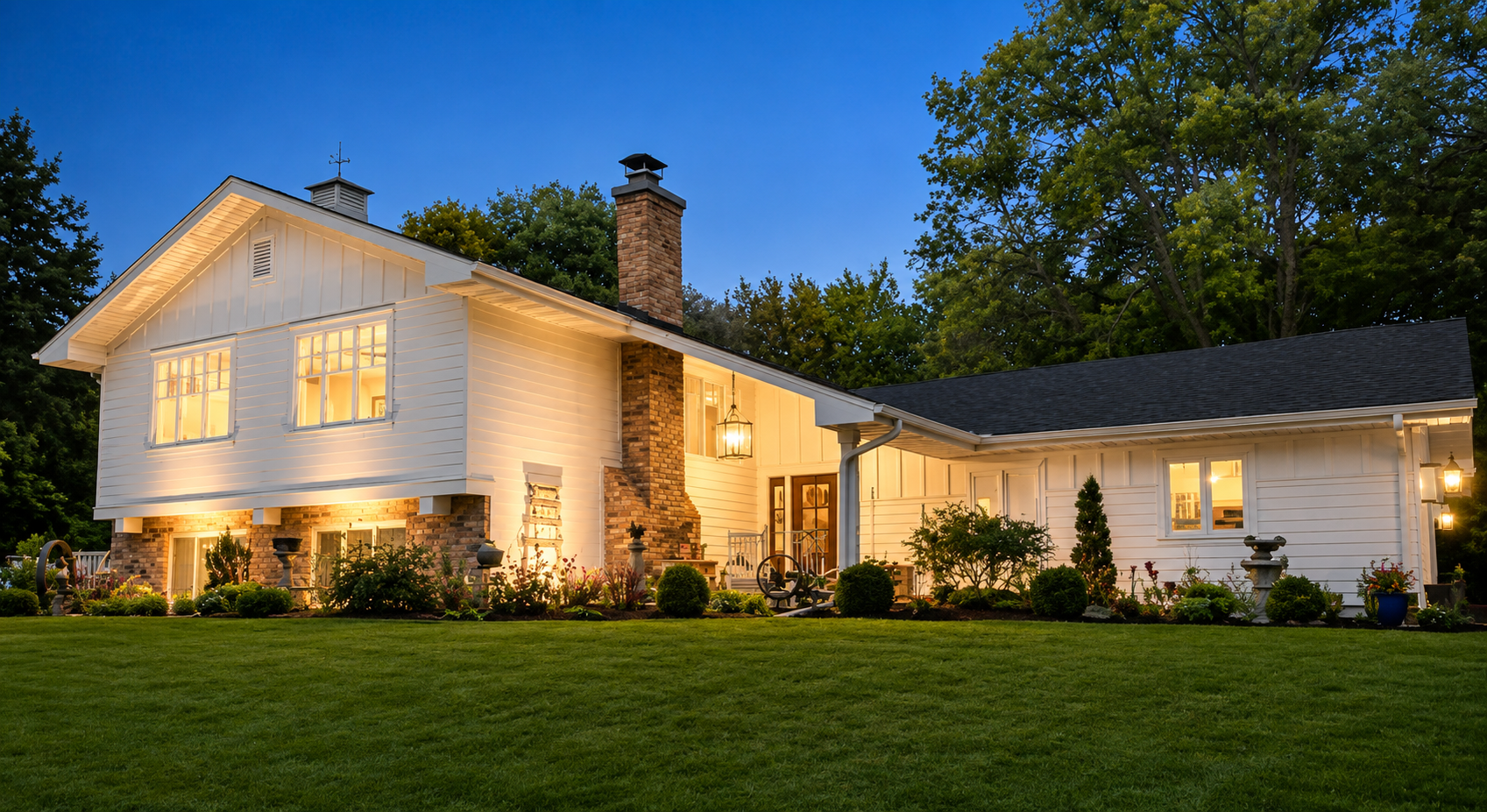White farmhouse style home lit at dusk with fresh white siding